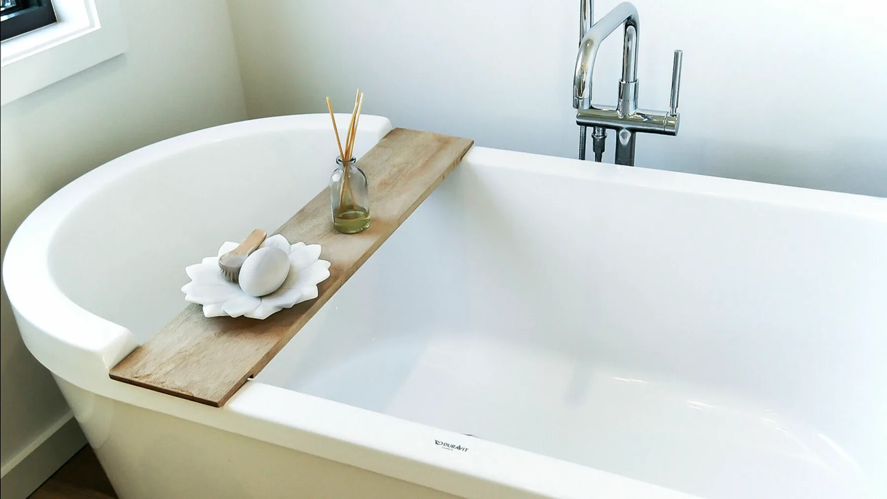 Una bañera con una bandeja de madera y un pequeño adorno.