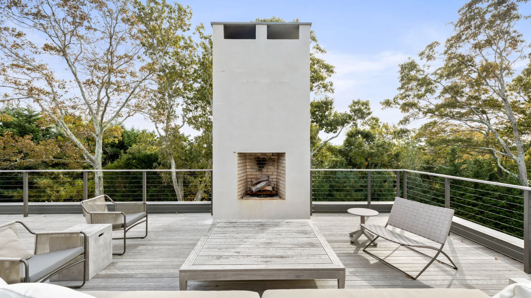 Una terraza al aire libre con asientos y una chimenea alta en el centro.