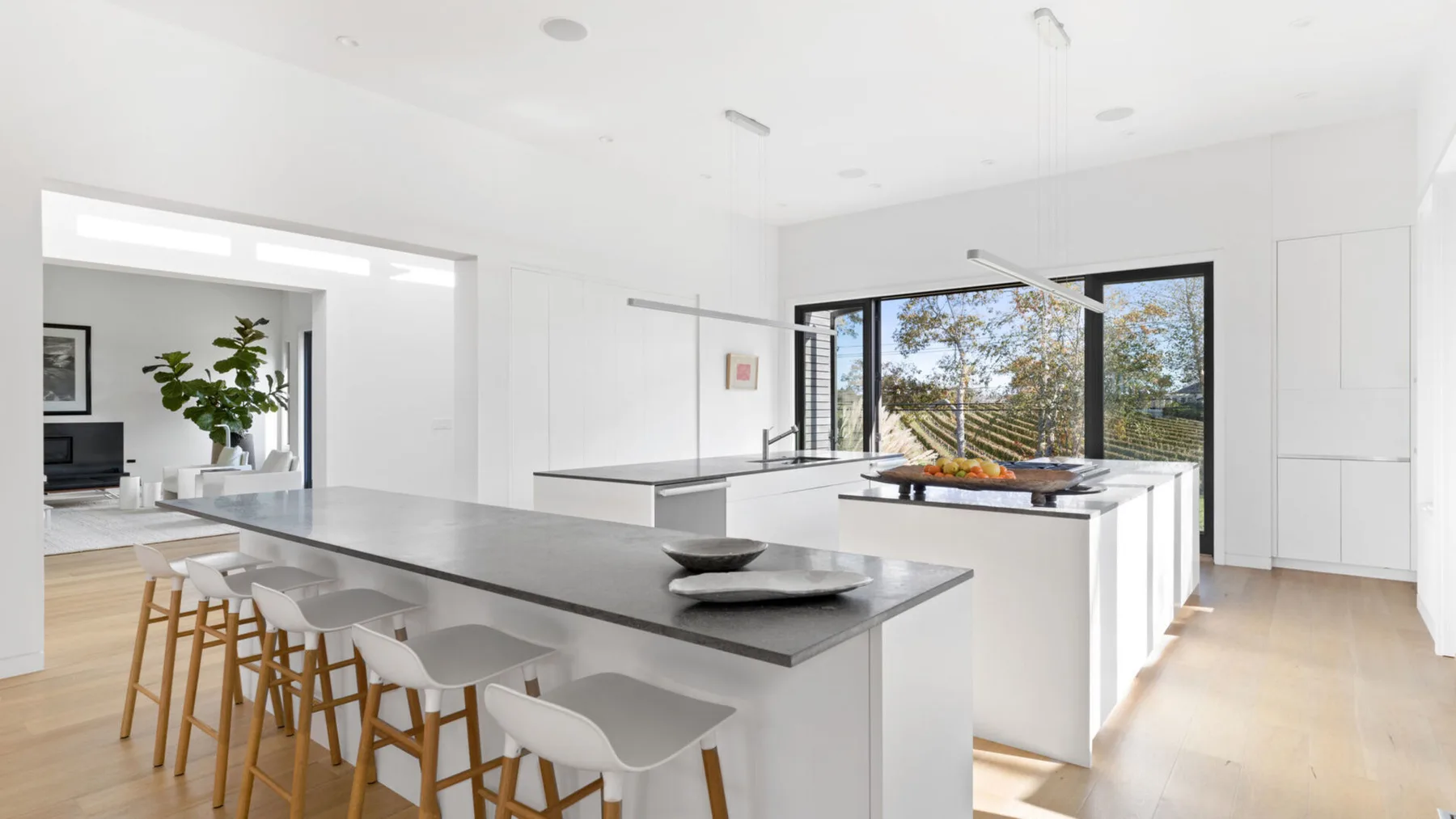 Una cocina moderna y luminosa tiene una isla grande con asientos y amplias ventanas.