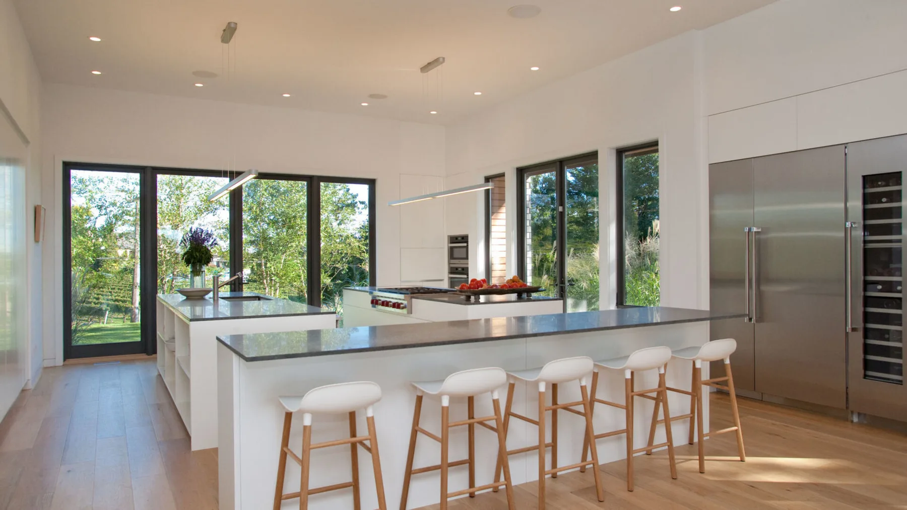 Una cocina moderna y luminosa con una isla grande y ventanas con vistas a la vegetación.