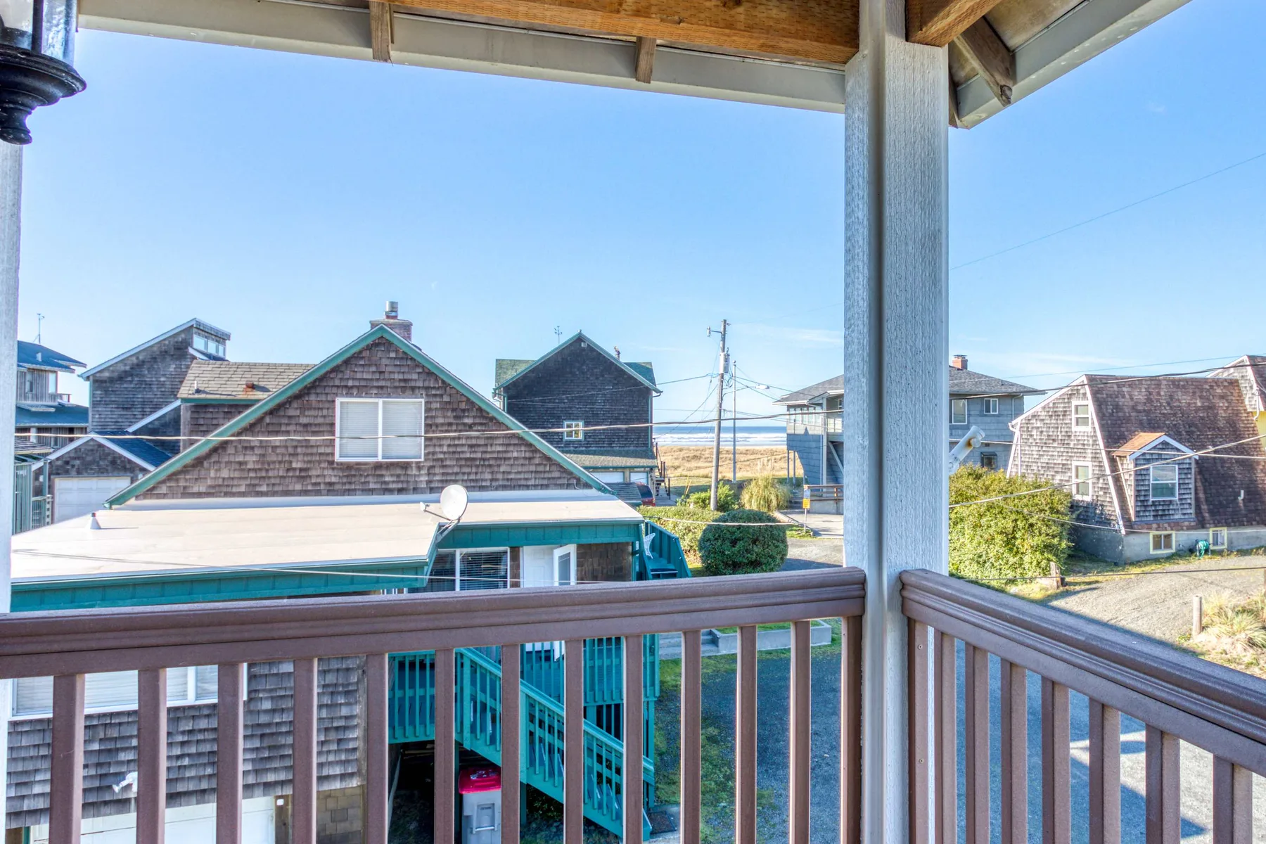A covered balcony overlooks neighboring houses under a clear sky.
