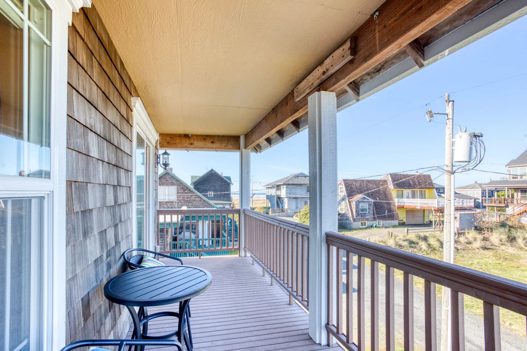 A covered balcony with wooden railings and views of nearby houses.