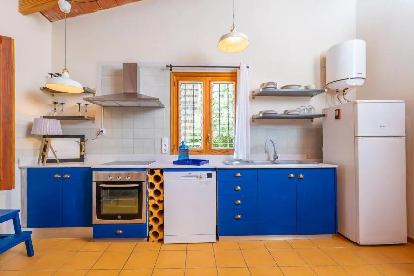 Una cocina luminosa con armarios azules, un fregadero y una ventana sobre la encimera.