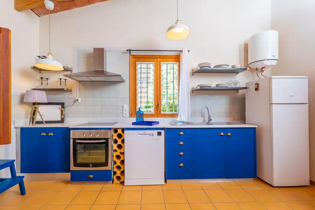 Una cocina con armarios azules, una estufa y una ventana sobre la encimera.