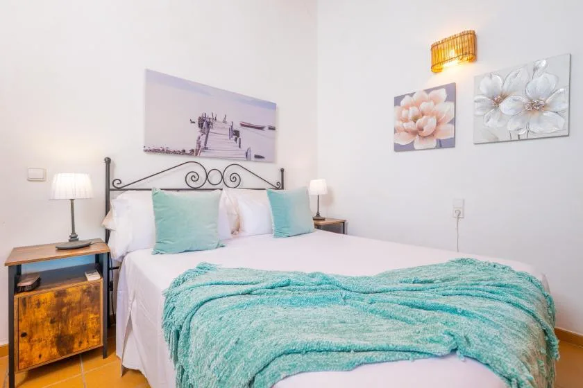 Un dormitorio con una cama vestida con ropa de cama blanca y turquesa.