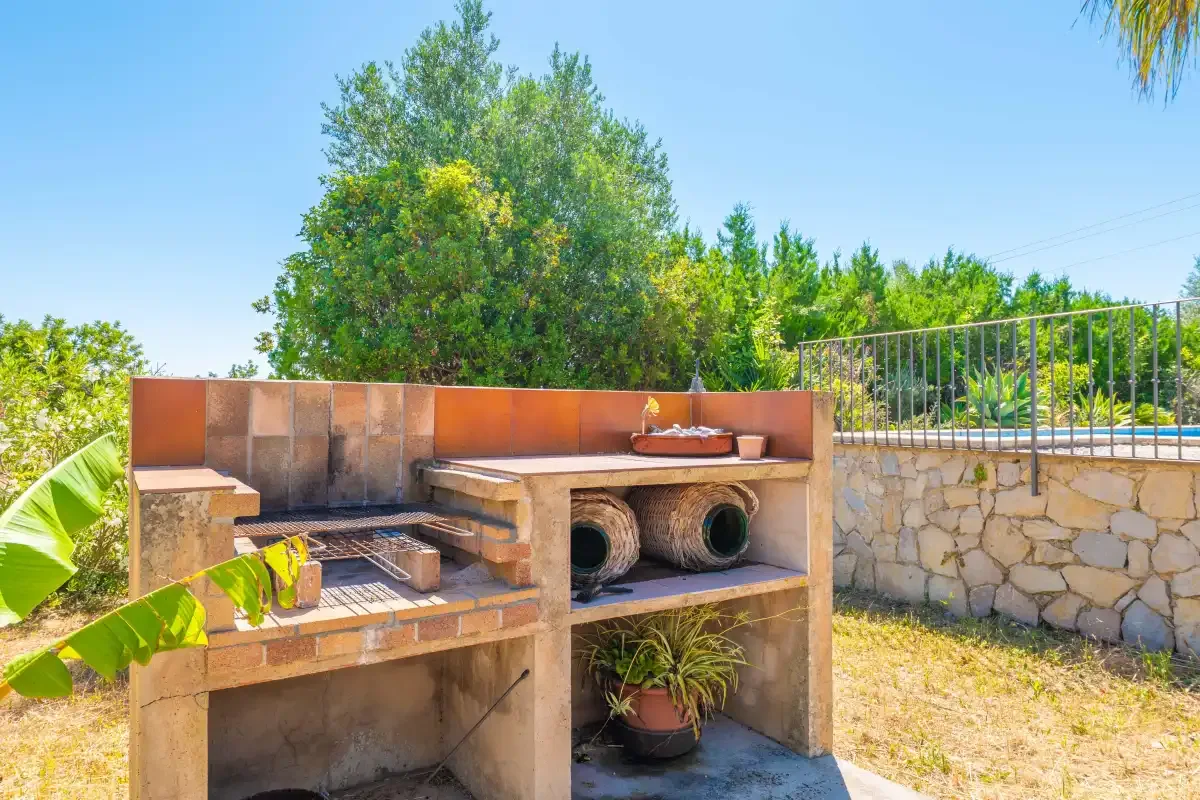 Una zona de cocina al aire libre con una encimera de azulejos y un muro de piedra.