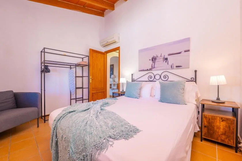 Un dormitorio con una cama, mesitas de noche y una zona de estar gris.