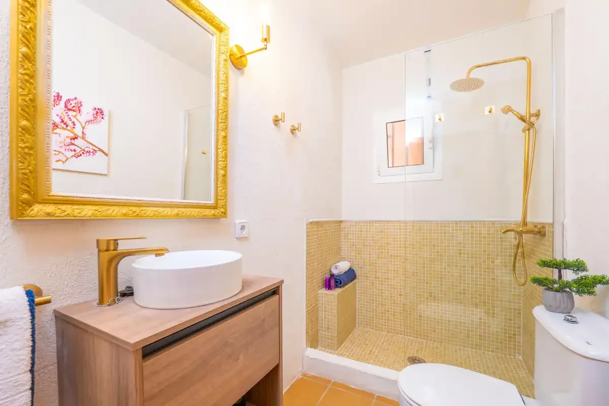 Un baño con lavabo, espejo enmarcado y ducha con azulejos.