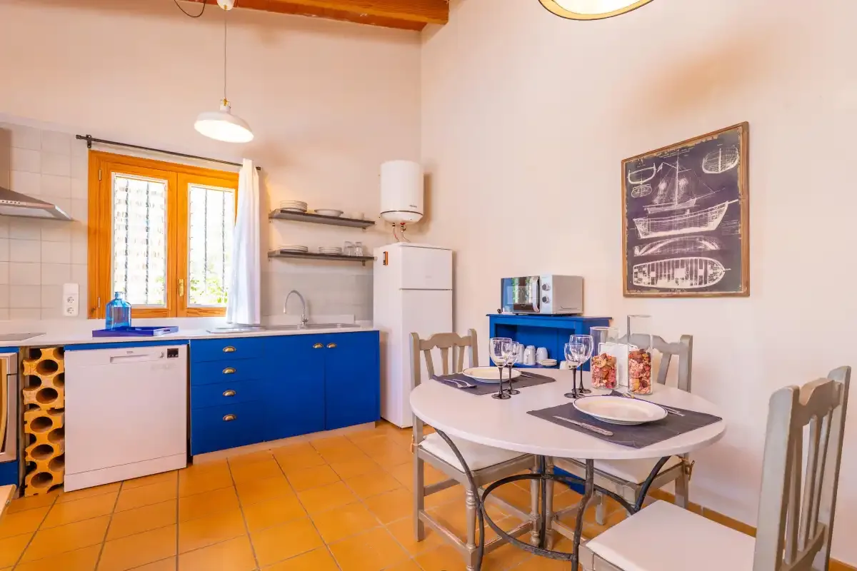 Una cocina y comedor con armarios azules y una mesa.