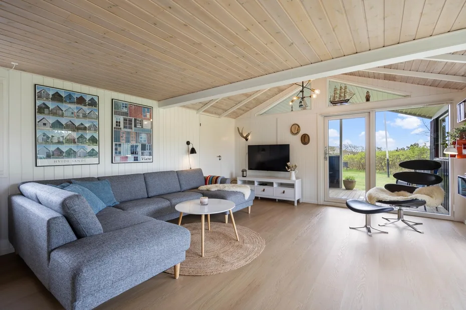 Una sala luminosa con asientos, un televisor y puertas de vidrio que dan a un patio.