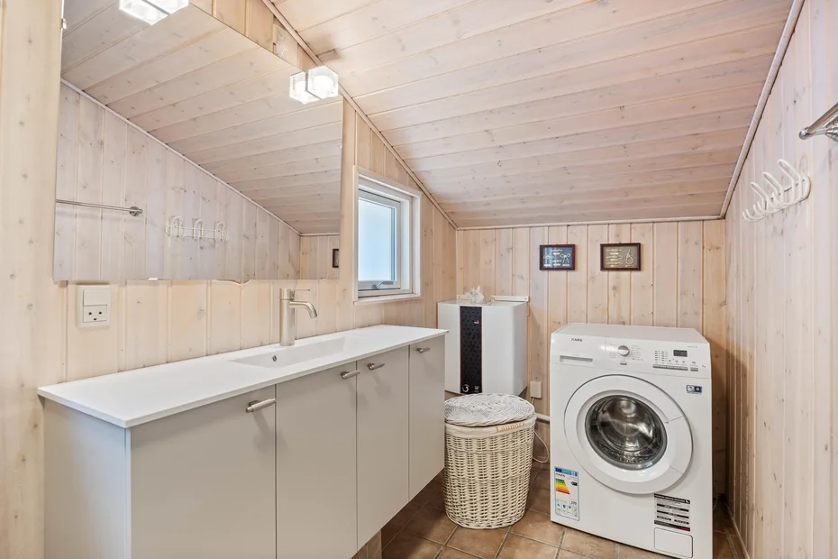 Un cuarto de lavandería revestido de madera con una lavadora y una encimera.