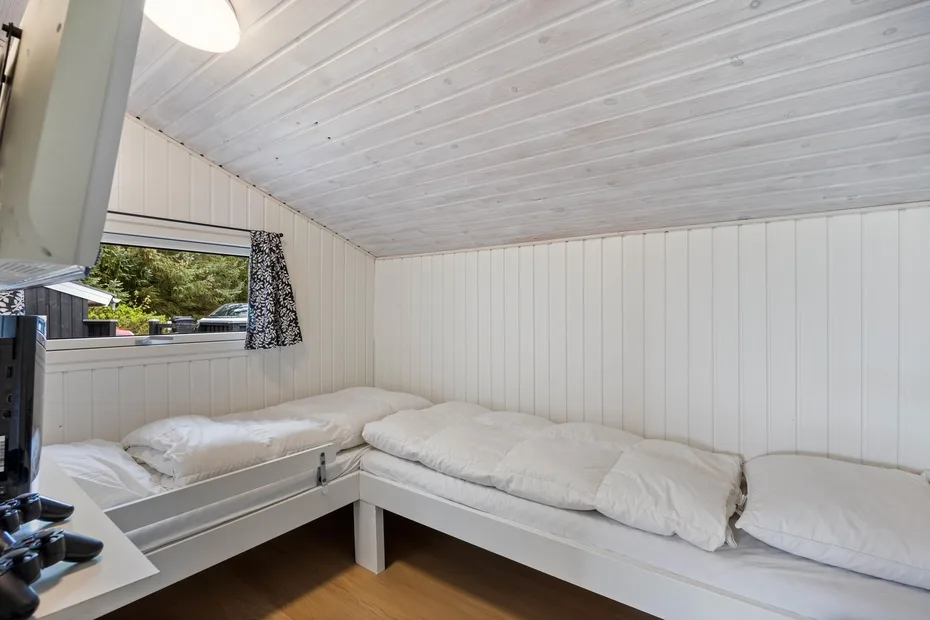 Un dormitorio compacto con ropa de cama blanca en dos camas contiguas.