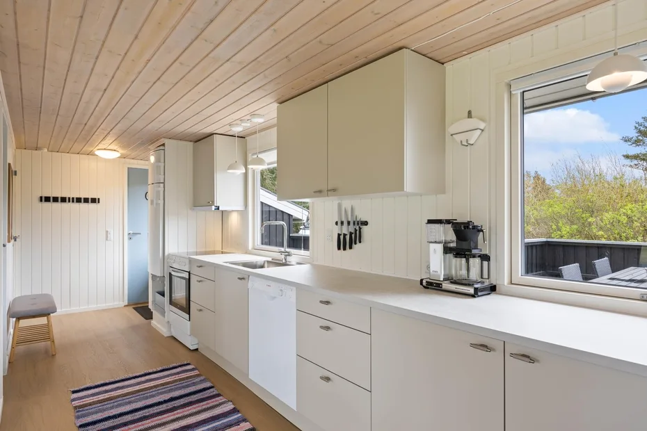 Una cocina luminosa con gabinetes blancos, una encimera y una ventana grande.