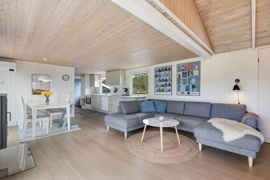 Un espacio abierto de sala y comedor con asientos seccionales y una cocina luminosa.