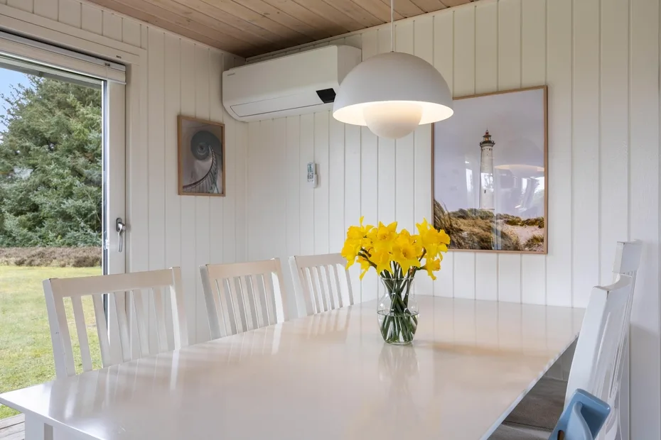 Un comedor luminoso con una mesa blanca y flores amarillas.