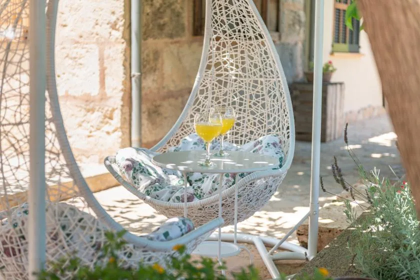 Una zona de estar al aire libre con una silla colgante y una mesa pequeña.