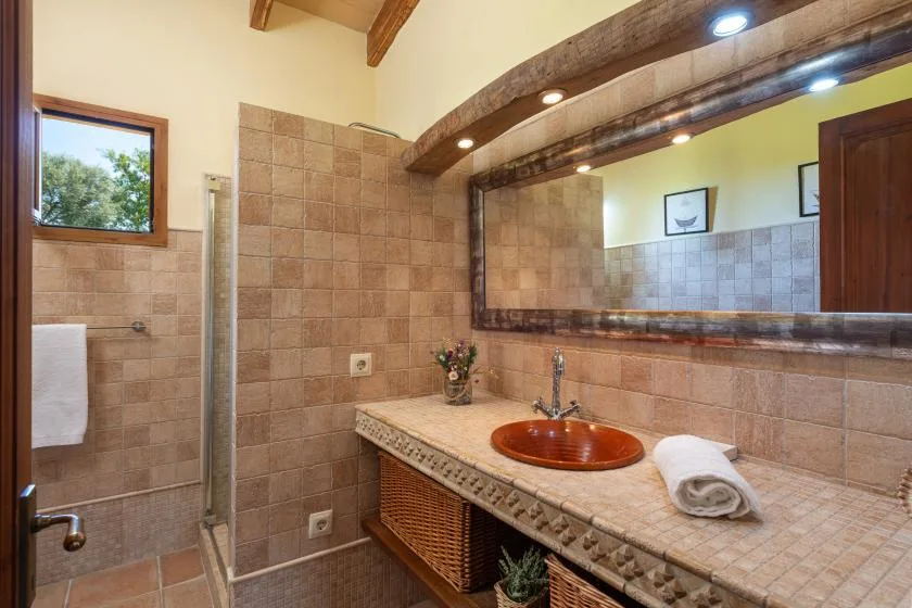 Un baño alicatado con un espejo grande y un lavabo integrado en la encimera.