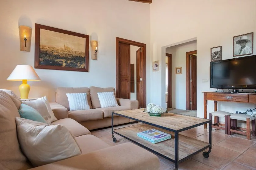 Una sala de estar con zona de asientos, mesa de centro y televisor.
