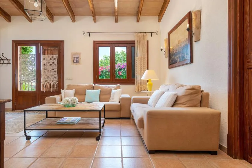 Una sala de estar con sofás, una mesa de centro y ventanas con vistas a la vegetación.