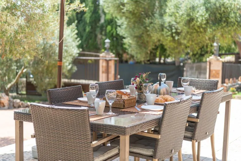 Un comedor al aire libre con una mesa puesta con platos y vasos.
