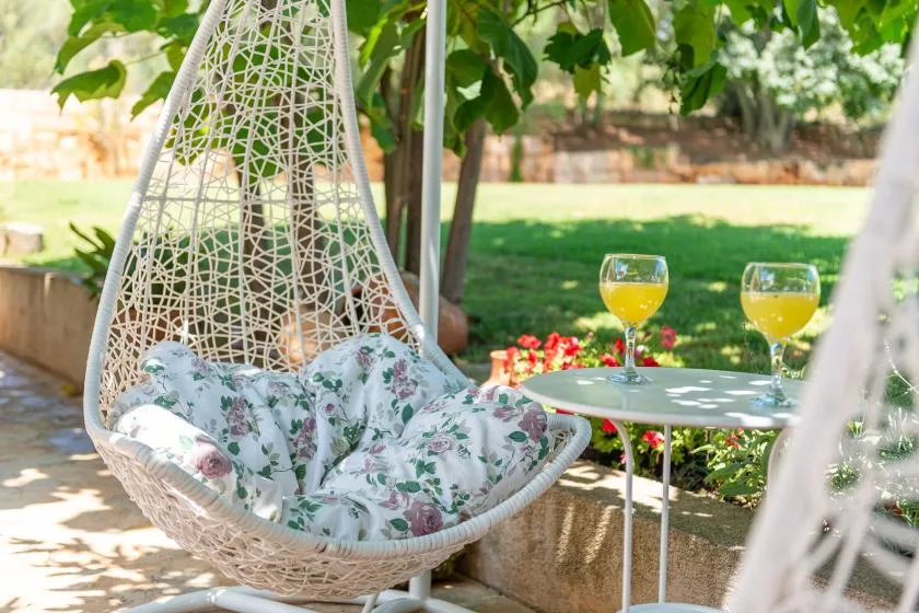 Una zona de descanso en el jardín con una silla colgante y una mesa pequeña.