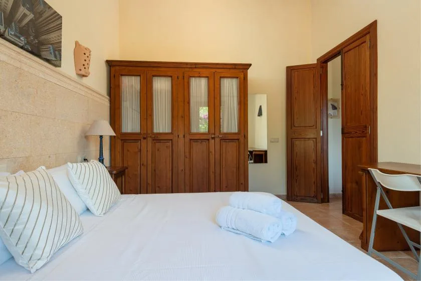Un dormitorio con una cama, toallas dobladas y armarios de madera.