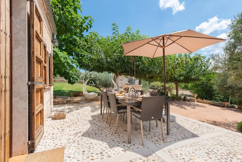 Una zona de comedor al aire libre con mesa y sillas bajo una sombrilla grande.
