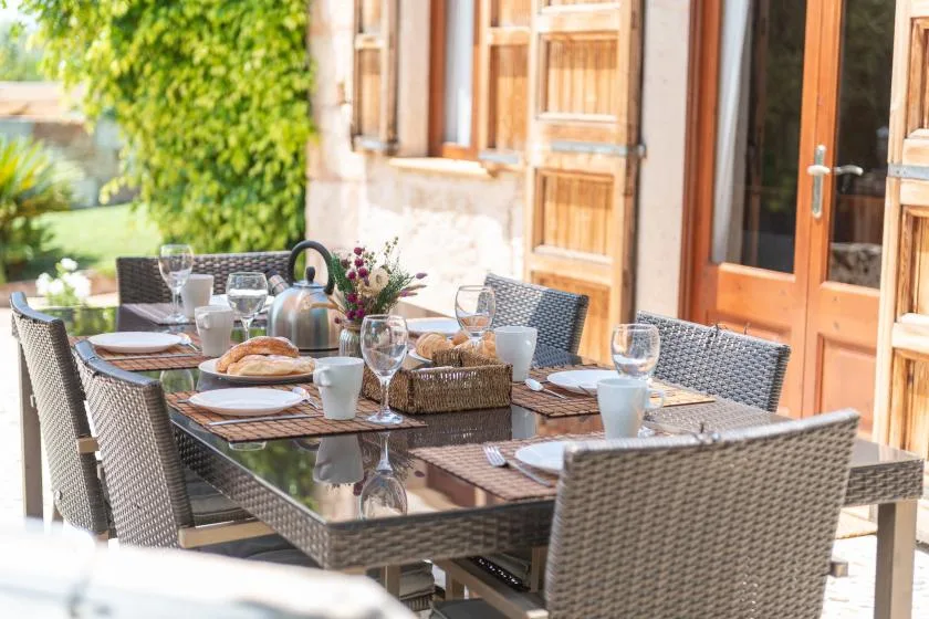 Una mesa de comedor al aire libre está preparada junto a una casa.