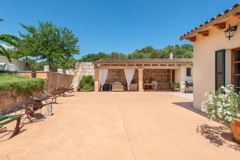 Un patio soleado con una zona de estar cubierta y plantas en macetas.
