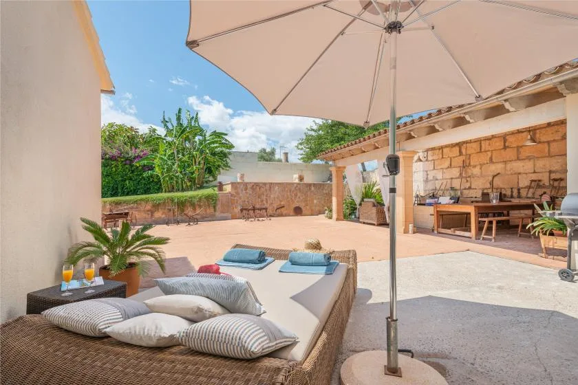 An outdoor patio with cushioned lounge seating, an umbrella, and a dining area.