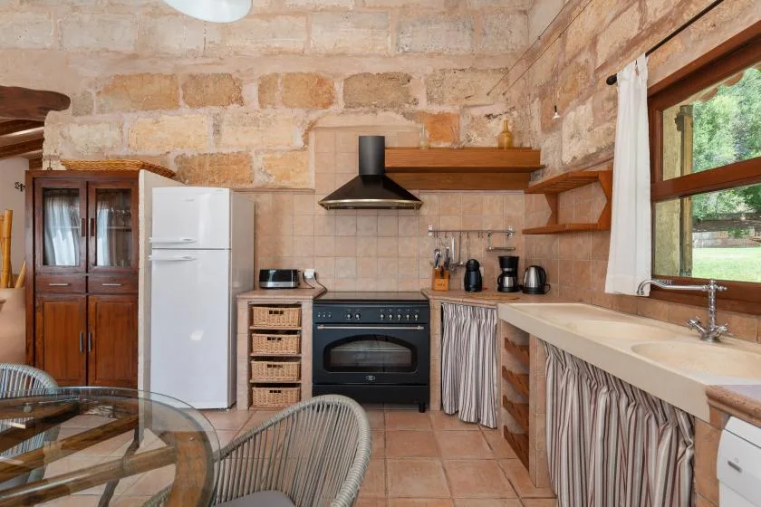 Una cocina rústica con estufa, refrigerador y encimera bajo una ventana.