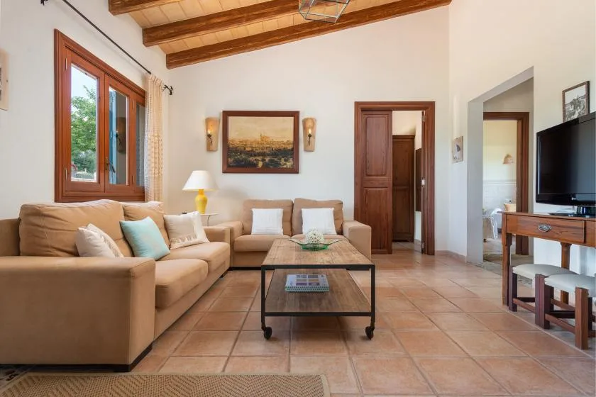 Una sala de estar con asientos beige y una mesa de centro bajo vigas de madera expuestas.