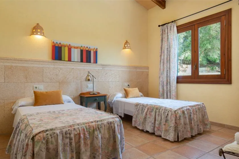 Un dormitorio con dos camas individuales, una mesita de noche y una ventana.