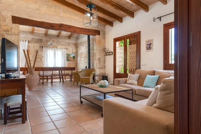 Una sala de estar con una zona de asientos y vigas de madera expuestas en el techo.