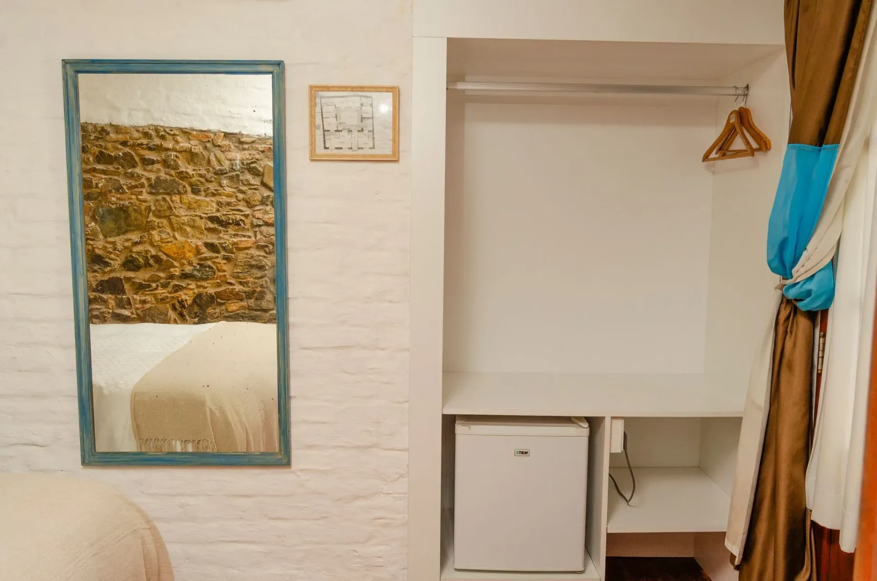 Habitación con un espejo que refleja la cama y un hueco para el minibar.
