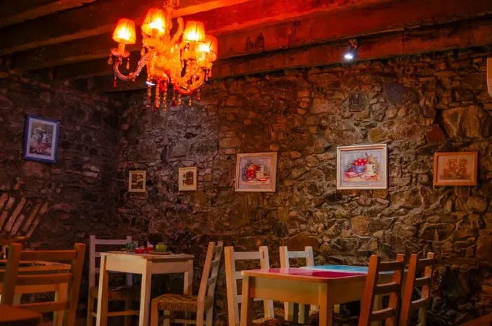 Comedor con paredes de piedra y mesas y sillas de madera.