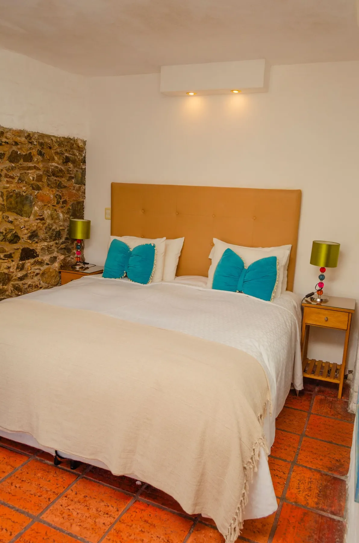 Habitación con una cama king size, pared de piedra y lámparas de noche.