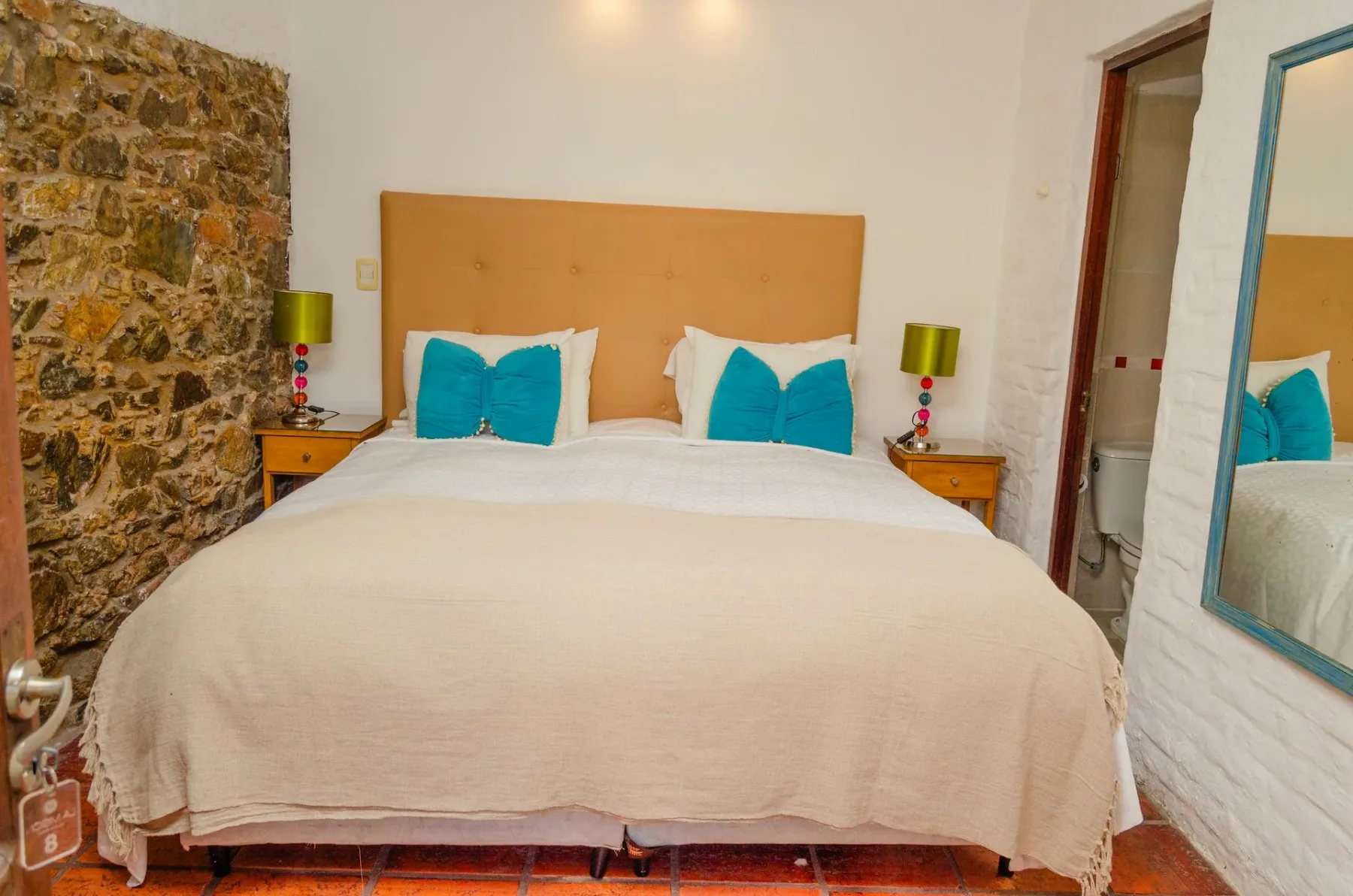 Habitación de hotel con una cama y pared de piedra.