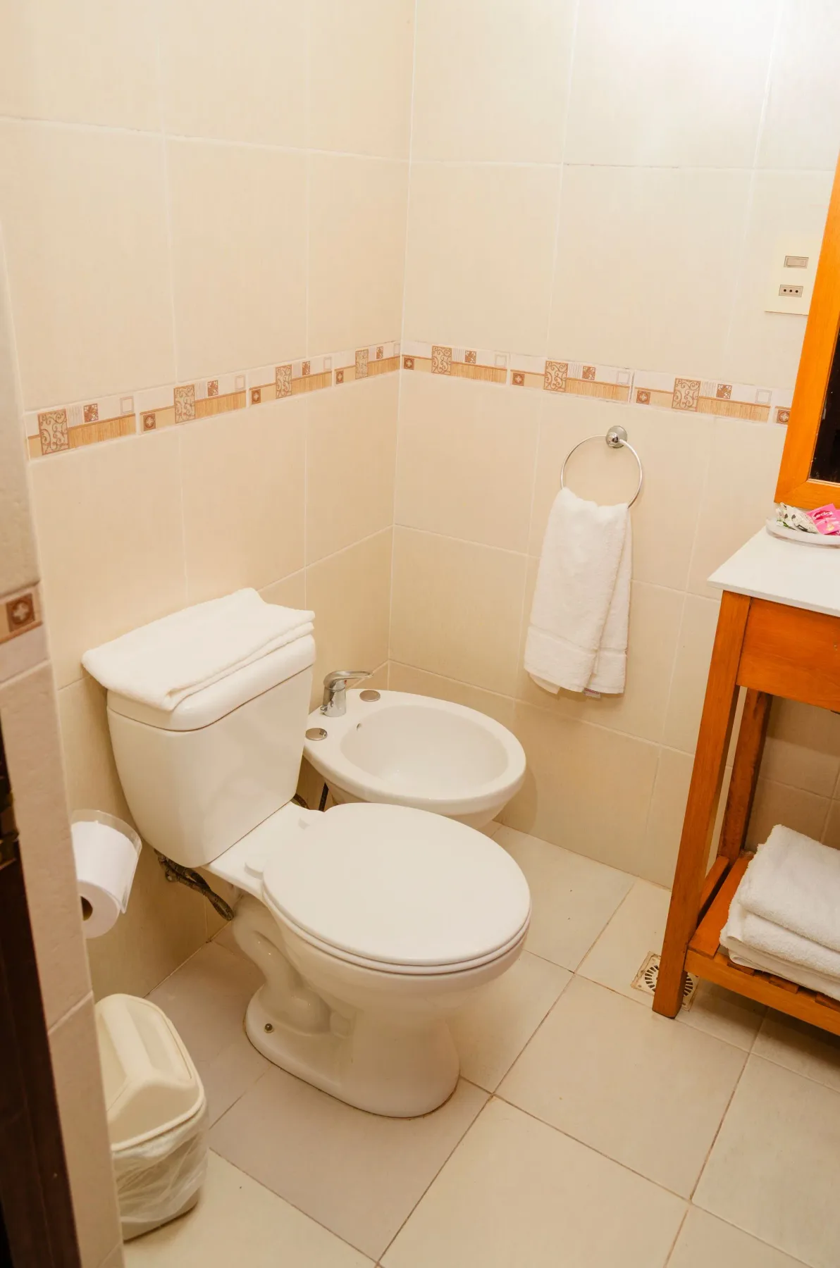 Baño con paredes revestidas de azulejos, bidé y mueble de lavabo.
