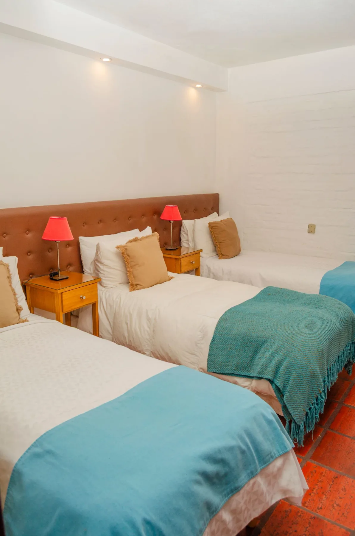 Habitación con tres camas individuales y mesitas de noche.