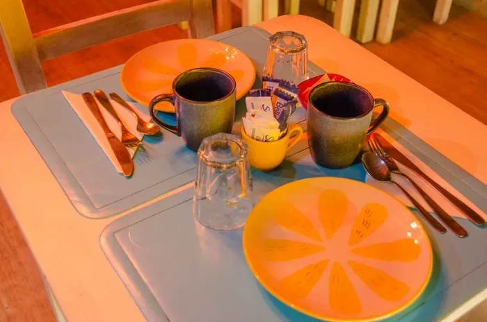 Mesa de desayuno con platos, tazas y cubiertos.