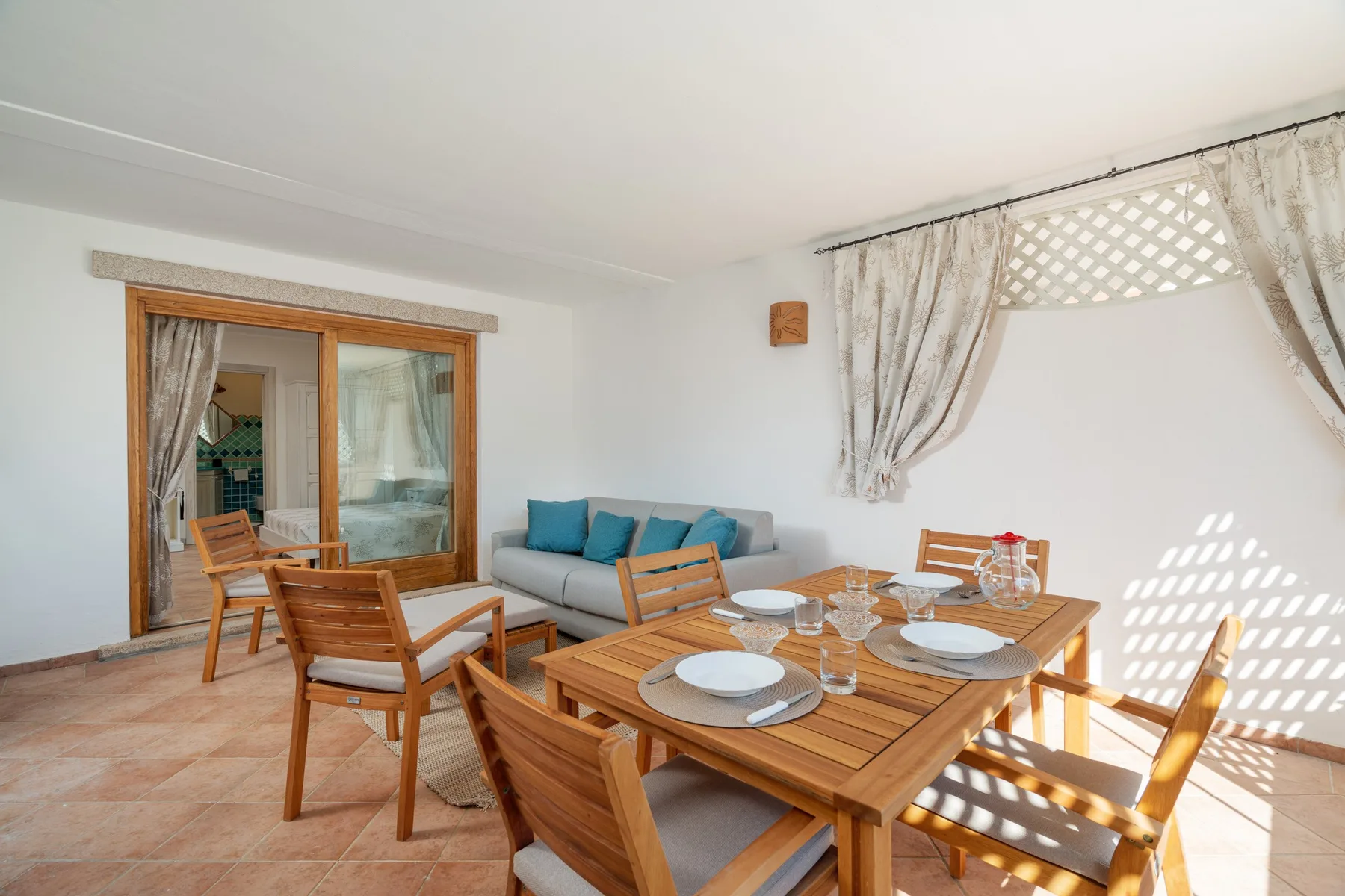 A dining area with a wooden table and seating beside a gray sofa.