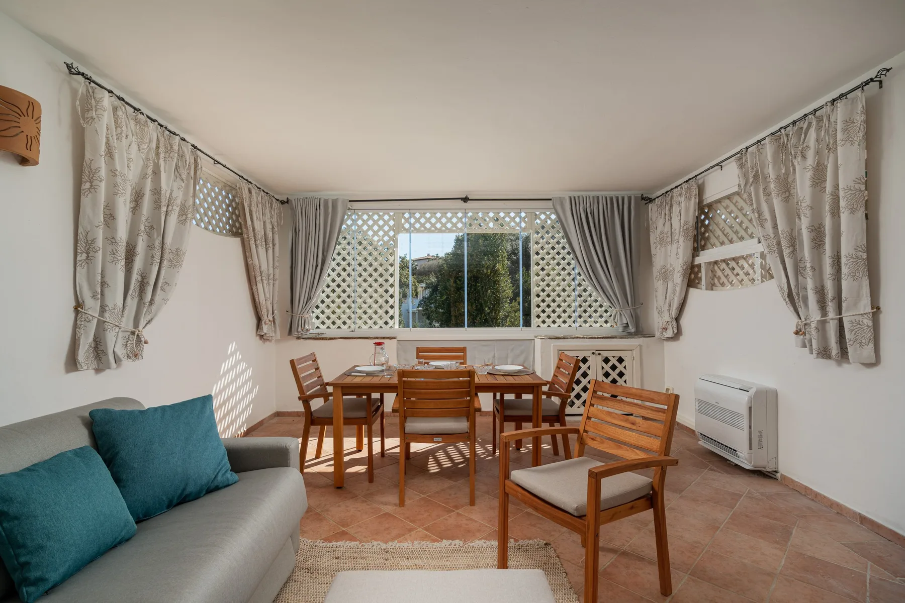 A sitting area with a dining table and chairs beside a large window.