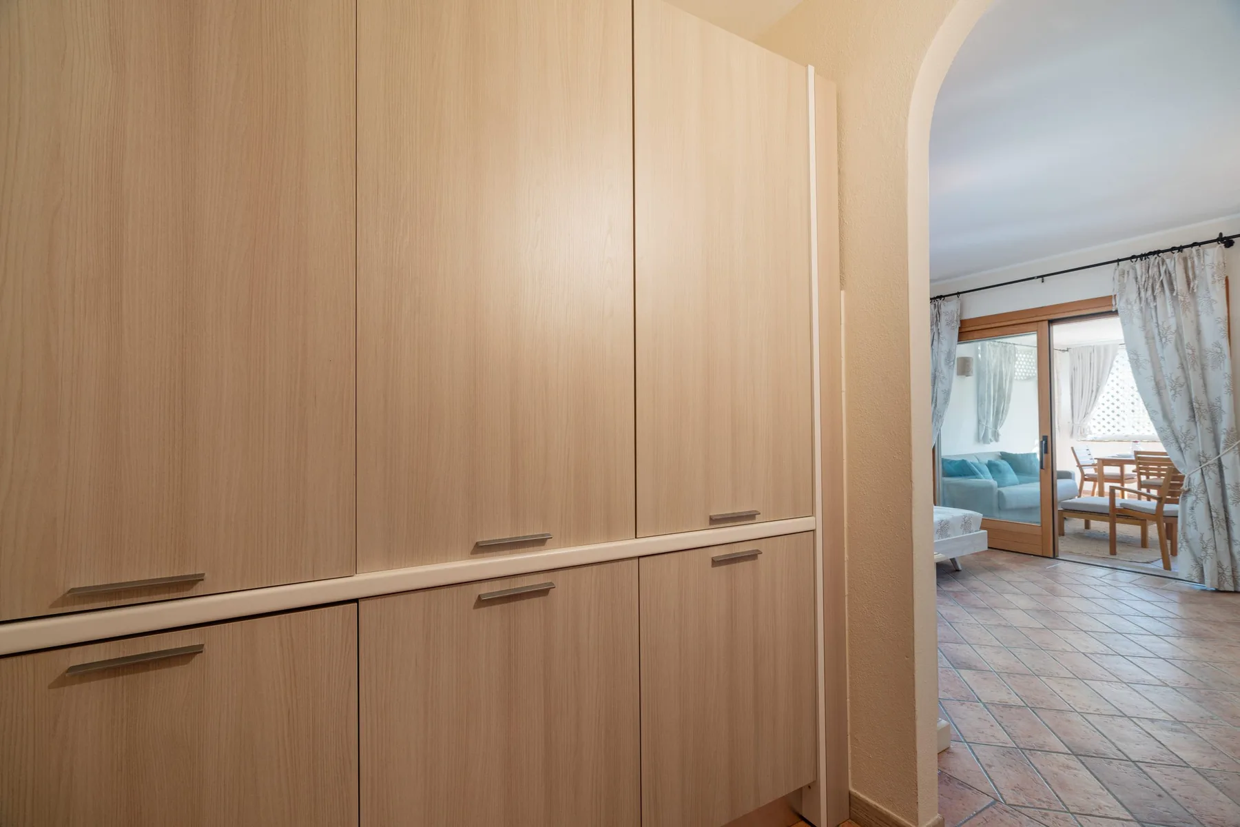 A built-in wardrobe beside an arched opening overlooks a bright sitting area.