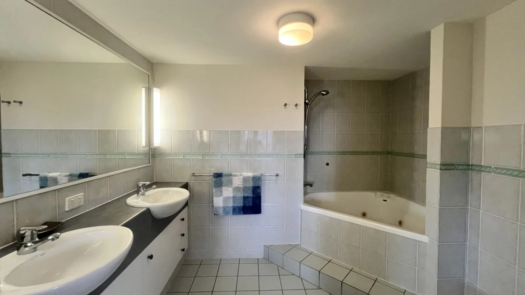 A tiled bathroom with a bathtub, shower, and two sinks.