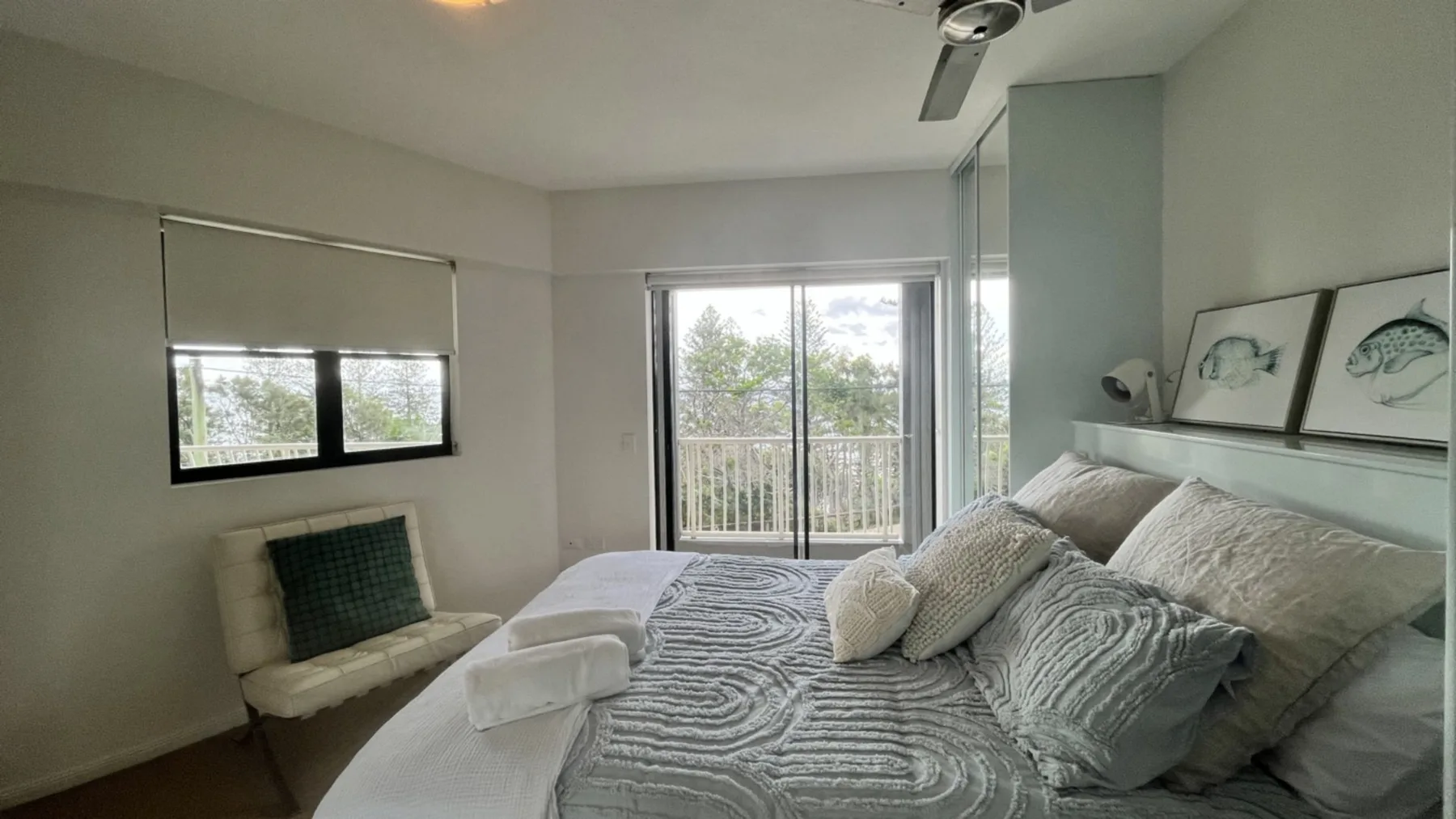 A bedroom with a large bed and sliding glass doors opening to a balcony.