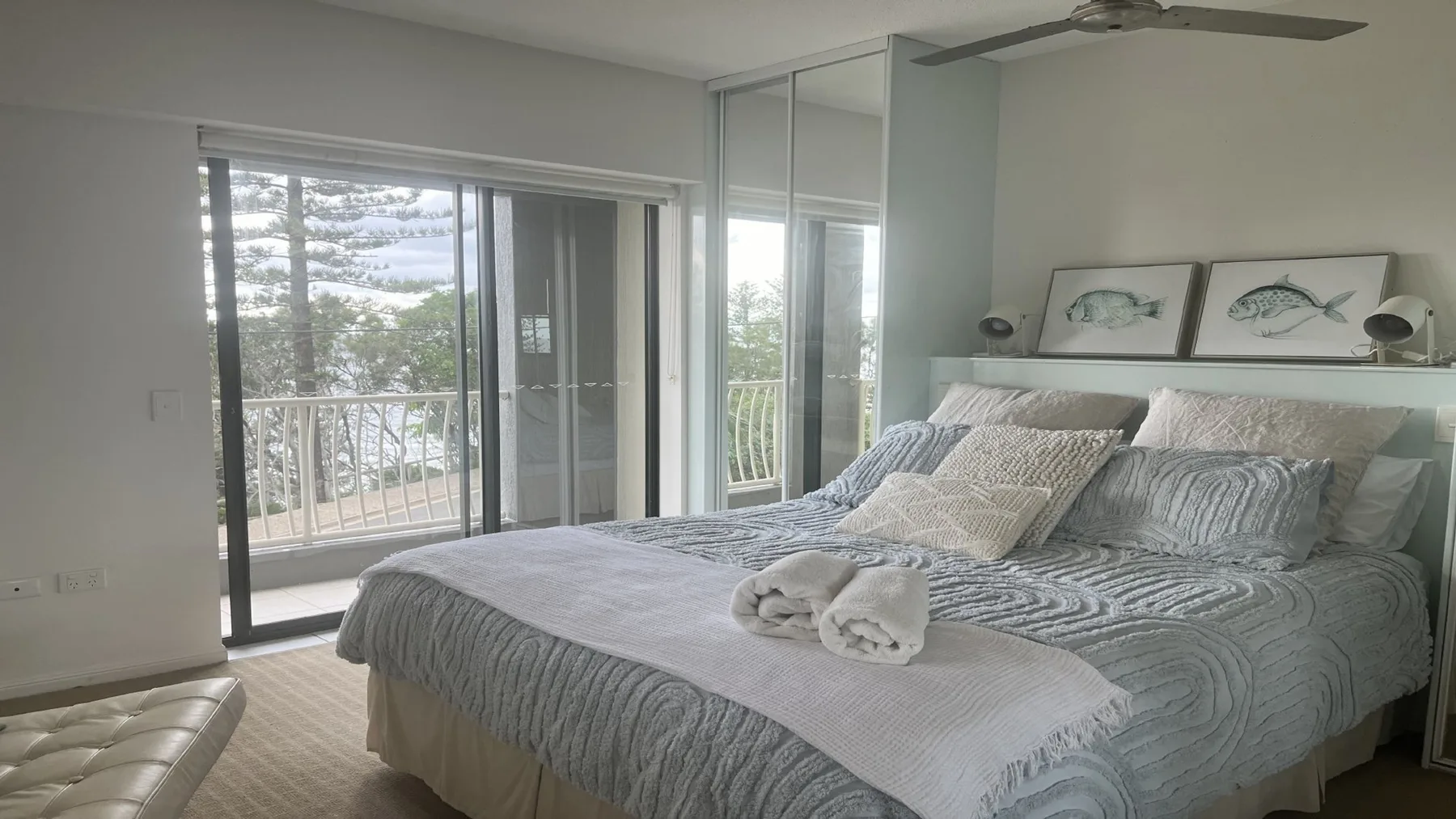 A bedroom with a large bed beside sliding glass doors opening onto a balcony.