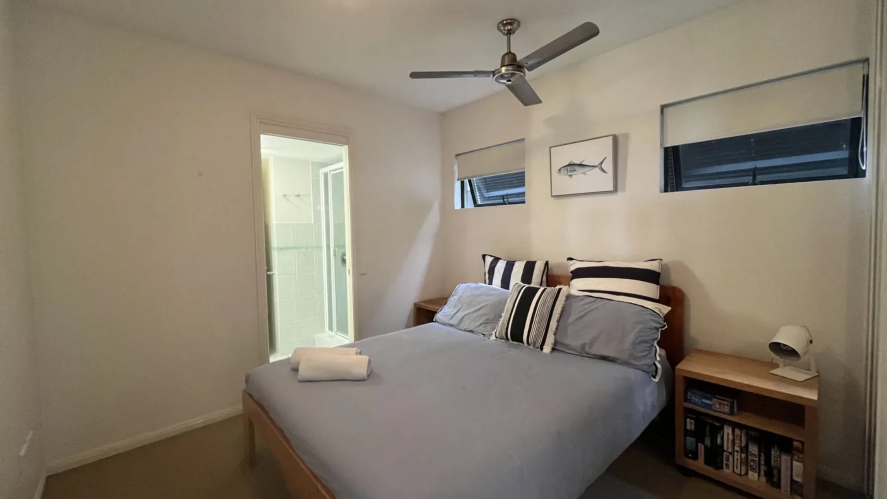 A bedroom with a neatly made bed and two windows.
