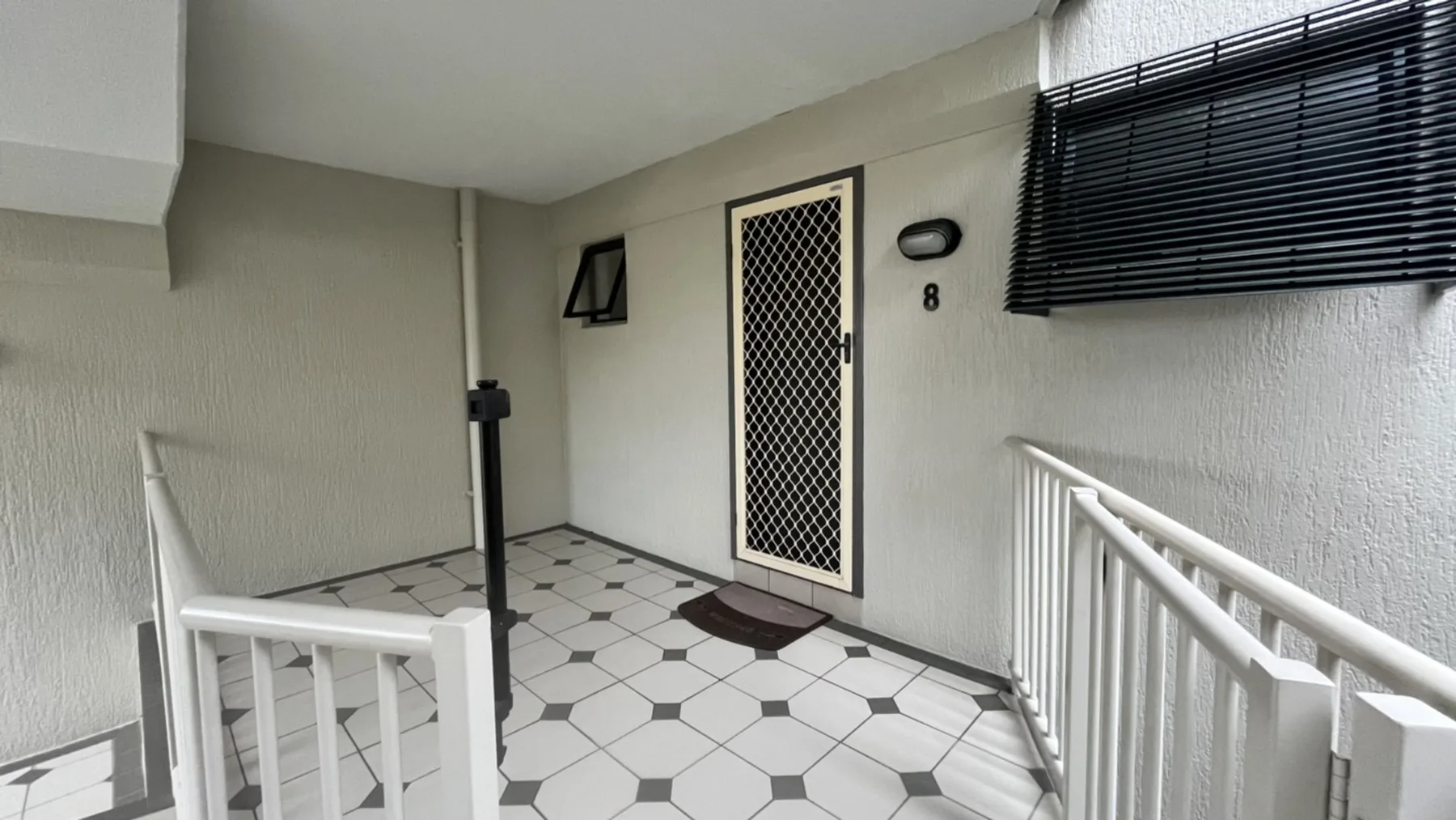 A covered entry walkway with a tiled floor and a mesh door.