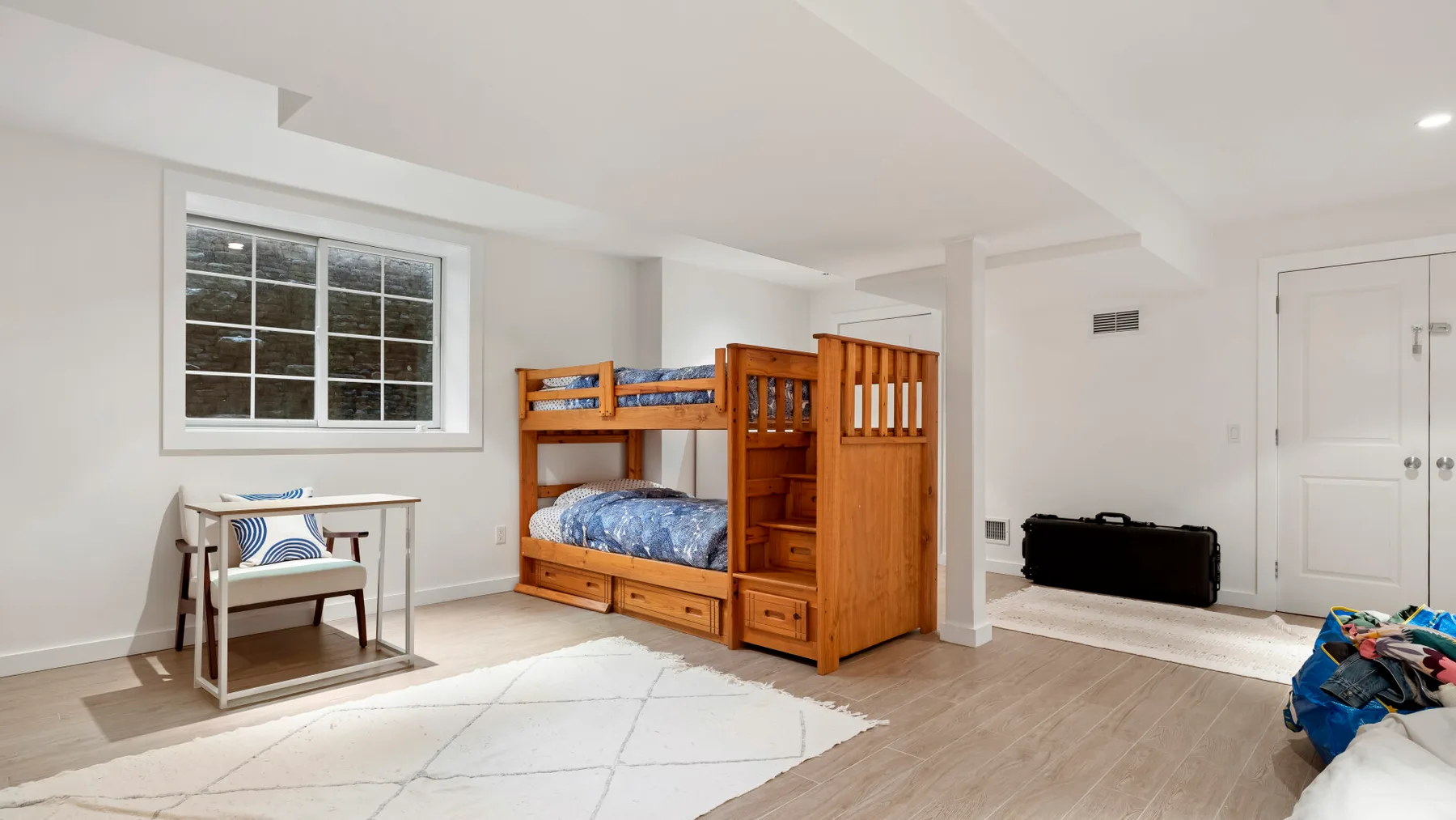 Un dormitorio luminoso con literas de madera y una ventana.